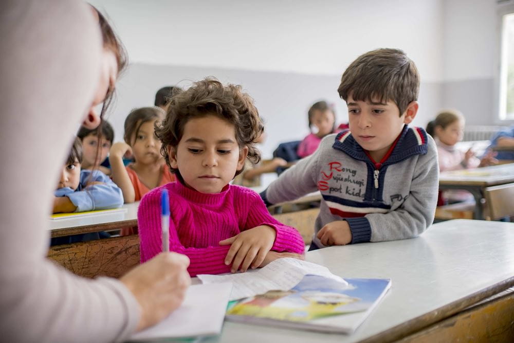 Zwei Kinder sitzen zusammen an einem Tisch in einem Klassenraum. Quelle: Jakob Studnar 