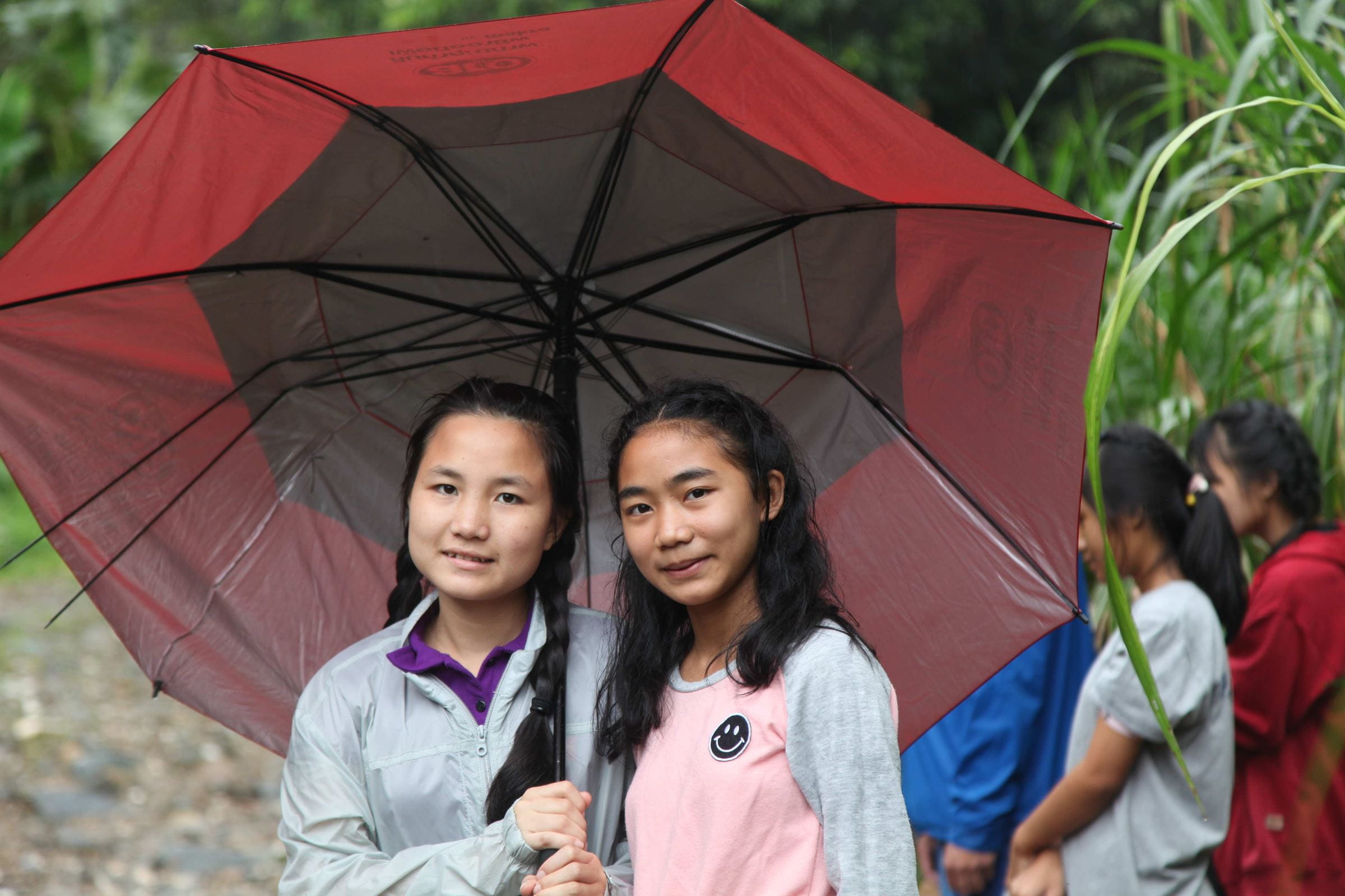 Zwei Mädchen teilen sich einen Regenschirm in Thailand. (Quelle: Kindernothilfe)