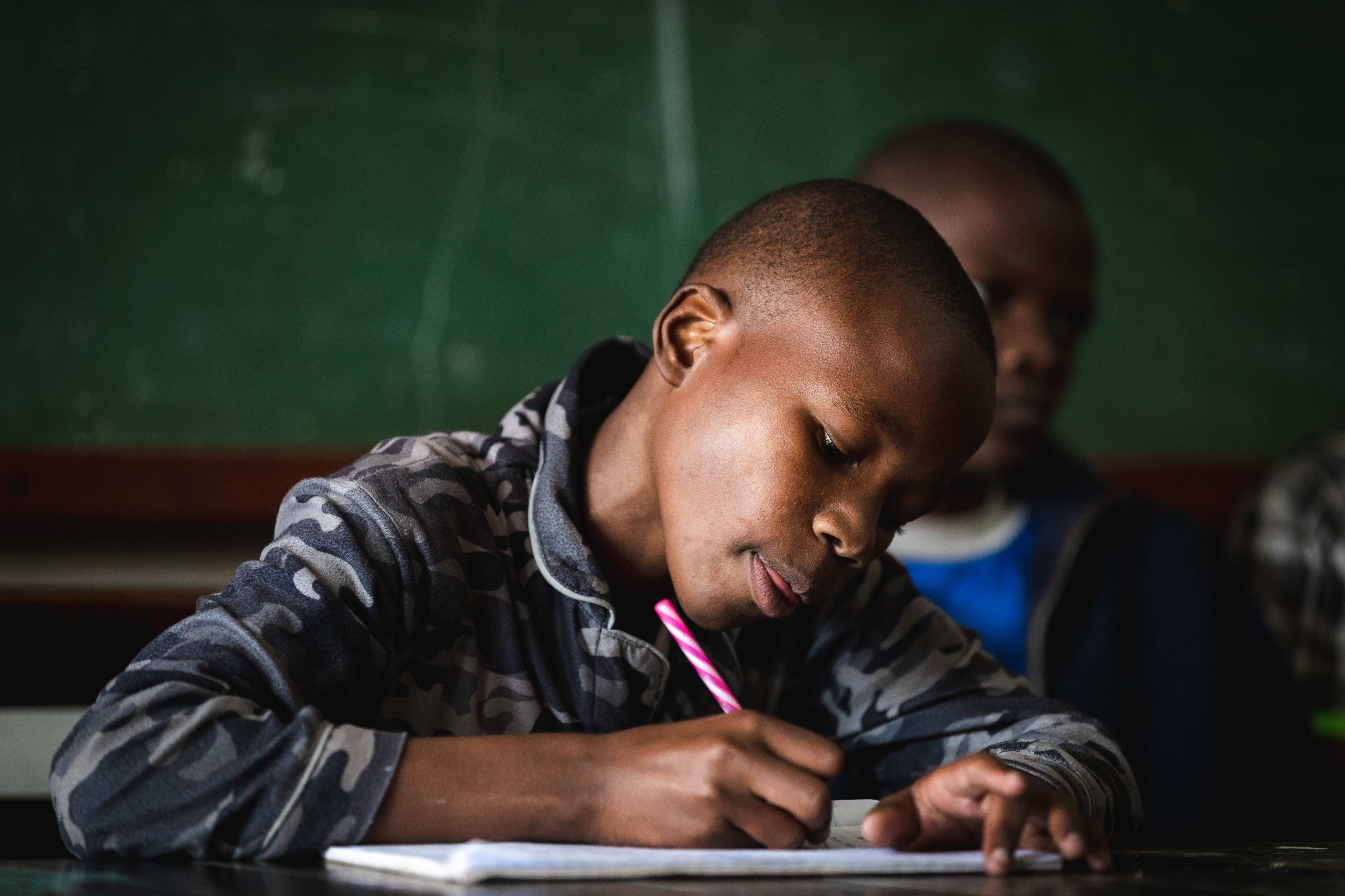 Kenianisches Kind notiert  etwas in einem Heft (Quelle: Lars Heidrich)