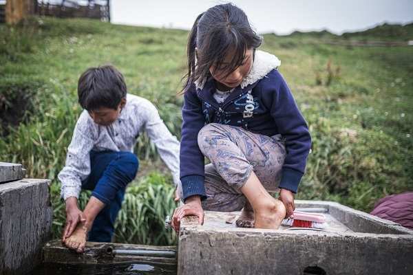 Zwei Kinder waschen draußen ihre Füße (Quelle: Martin Bondzio)