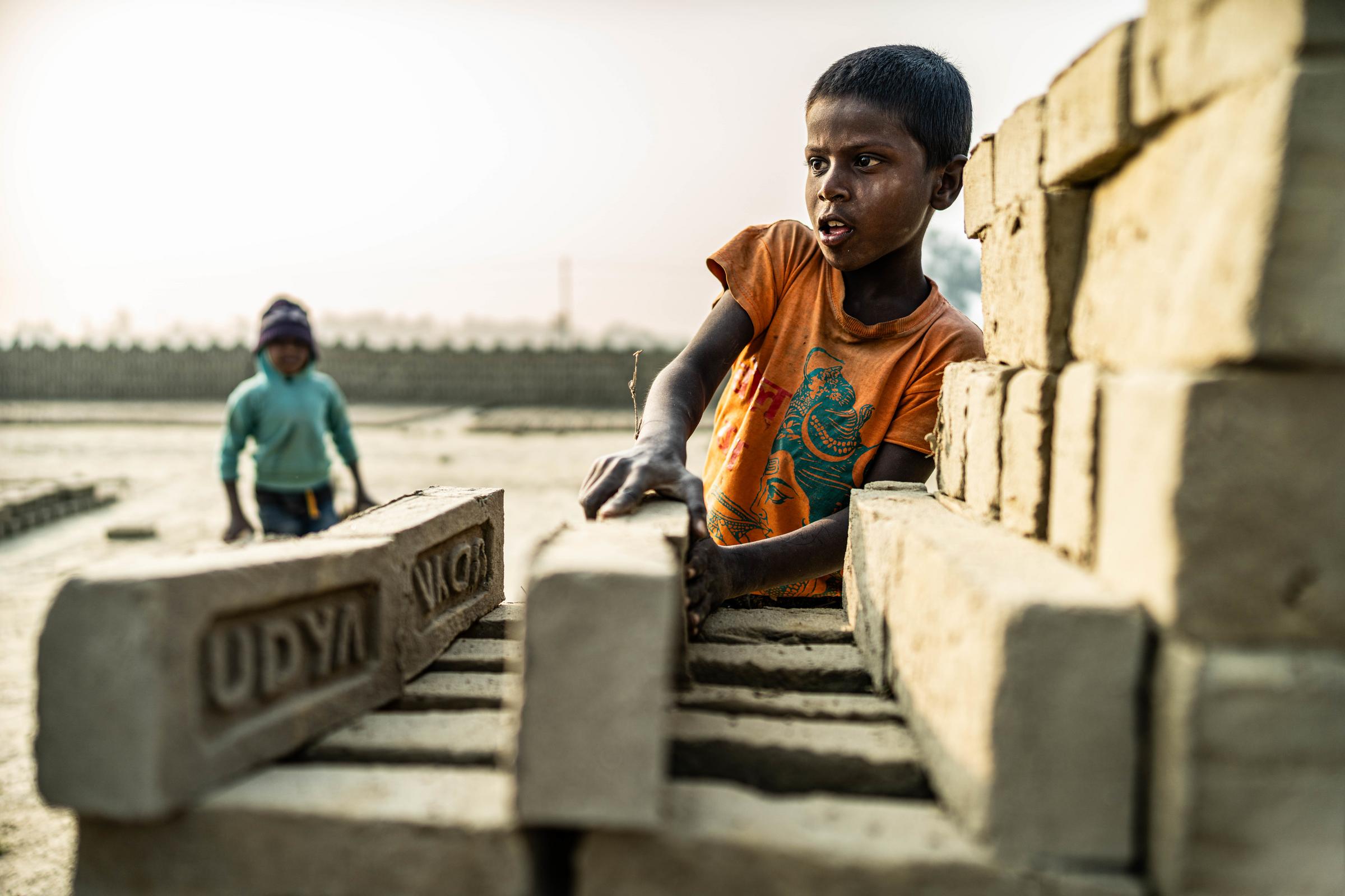 Junge in der Ziegelei stapelt Ziegel Foto : Jakob Studnar / Kindernothilfe.