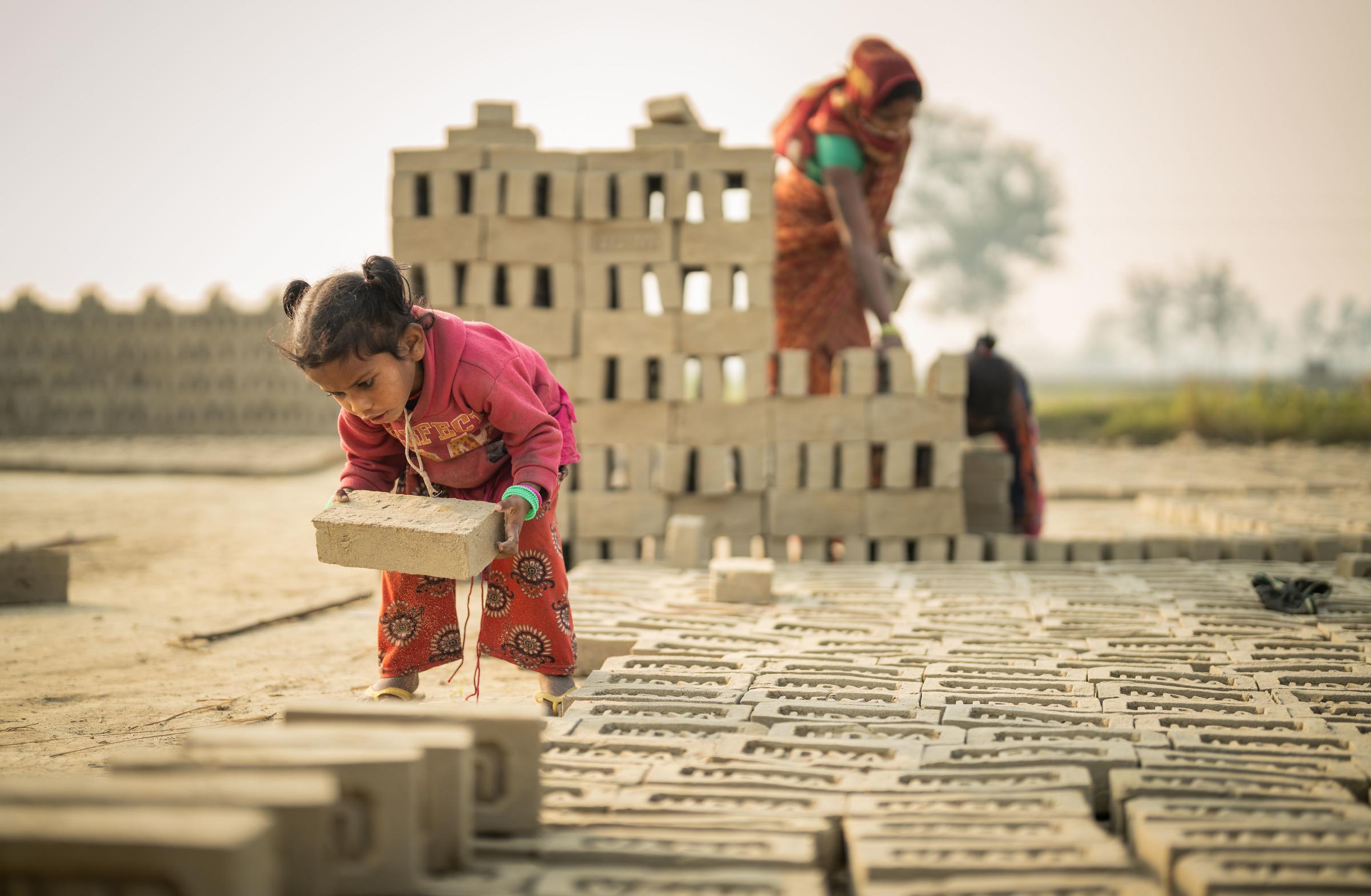 Mädchen trägt schweren Ziegel (Quelle: Jakob Studnar)