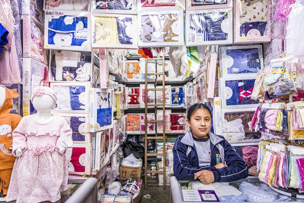 Junges Mädchen sitzt an Ladentheke eines Klamottengeschäfts (Quelle: Kindernothilfe) Junges Mädchen sitzt an Ladentheke eines Klamottengeschäfts (Quelle: Kindernothilfe)