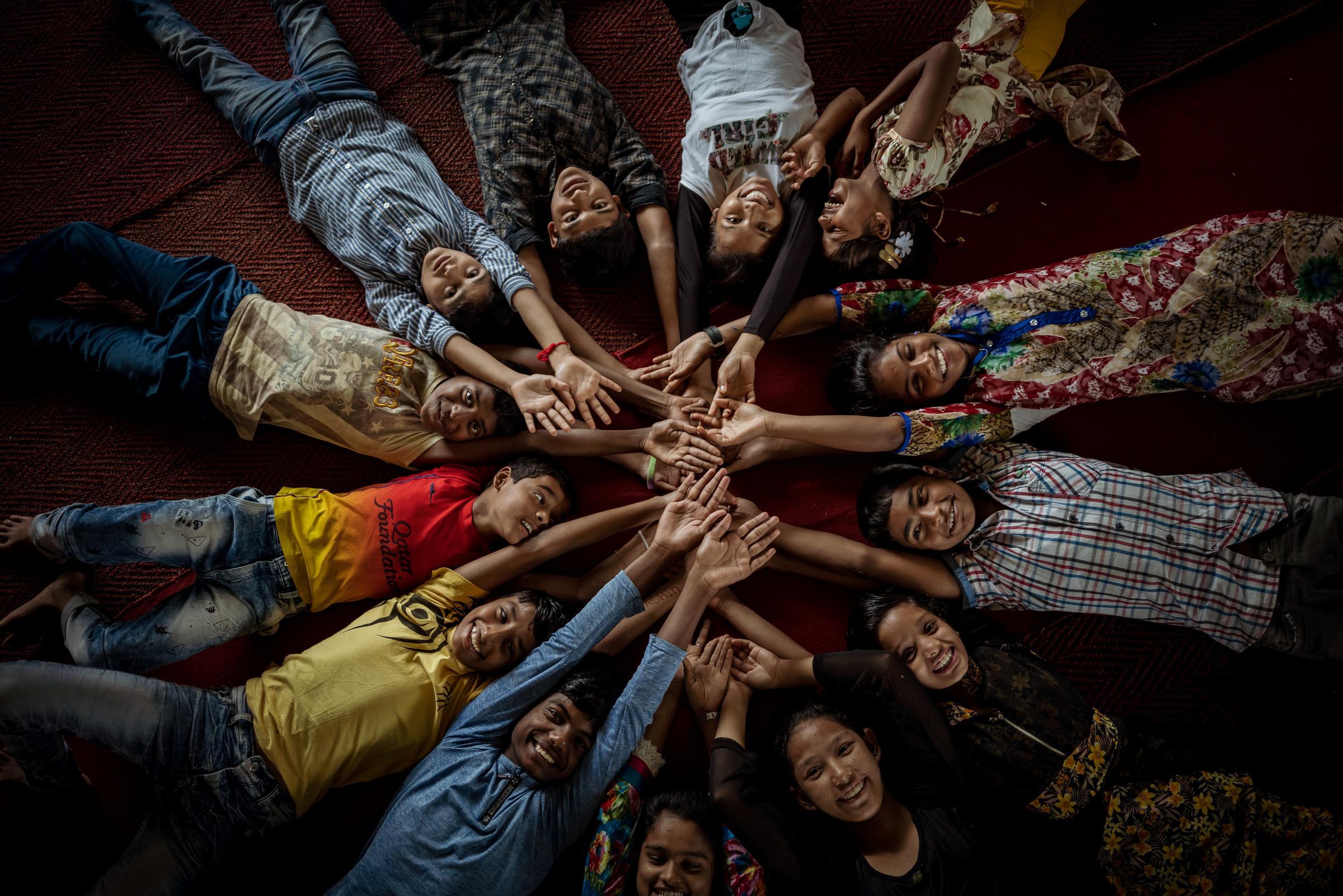 Kinder aus Indien liegen auf dem Rücken im Kreis mit den Armen in die Mitte gestreckt (Quelle: Jakob Studnar) Kinder aus Indien liegen auf dem Rücken im Kreis mit den Armen in die Mitte gestreckt (Quelle: Jakob Studnar)