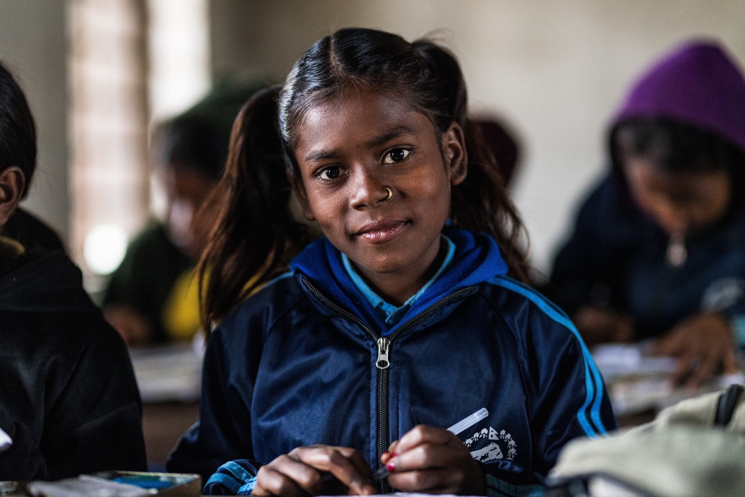 Gamya, ein Mädchen aus Nepal, ist froh, dass sie nicht mehr arbeiten muss. Die Schule macht ihr viel Freude. Auf dem Bild sitzt sie im Klassenraum und schaut in die Kamera. (Foto: Martin Bondzio)