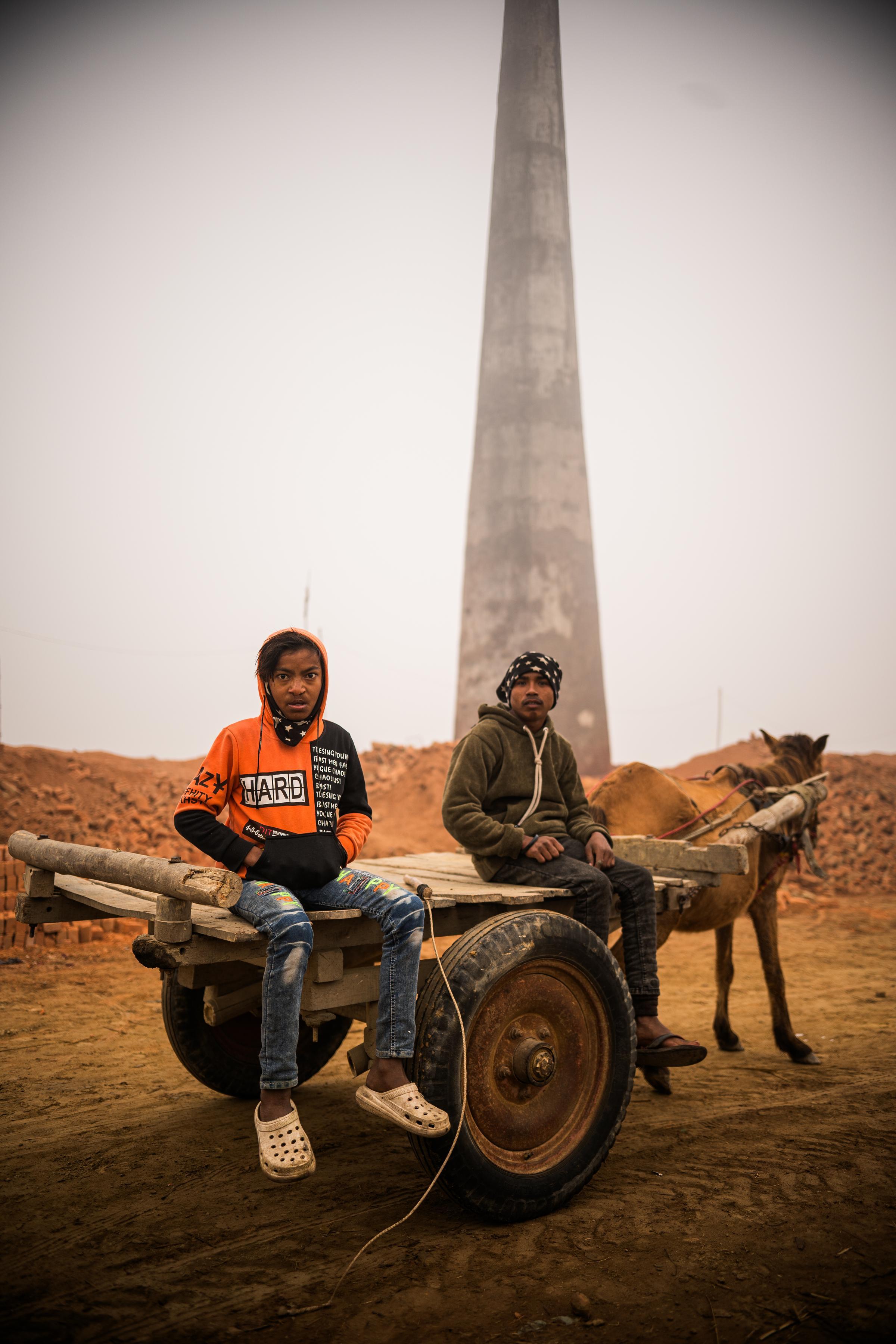 Anil und sein Freund Tej sitzen auf dem Pferdekarren und schauen in die Kamera. Sie sind ein eingespieltes Team in der Ziegelei. Anstatt zu arbeiten, würden sie lieber gemeinsam Fußball spielen. (Foto: Martin Bondzio)