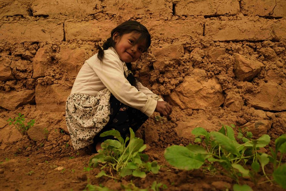 Ein kleines Mädchen sitzt vor einem Gemüsebeet. (Quelle: Mauricio Vera)