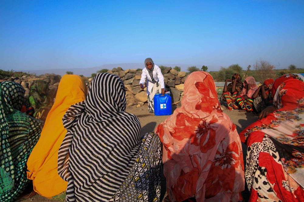 Äthiopische Frauen in bunten Gewändern sitzen um eine weitere Frau herum, die einen Wasserkanister festhält. (Quelle: Girmay Tilahun)