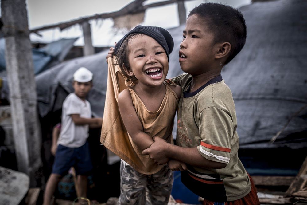 Zwei Jungen halten sich lachend im Arm. Um sie herum herrscht Chaos nach dem Taifun Haiyan auf den Philippinen. (Quelle: Jakob Studnar)